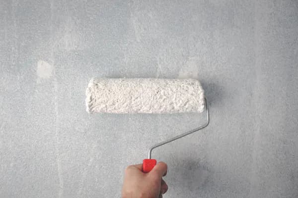 Person streicht Wand mit Farbrolle