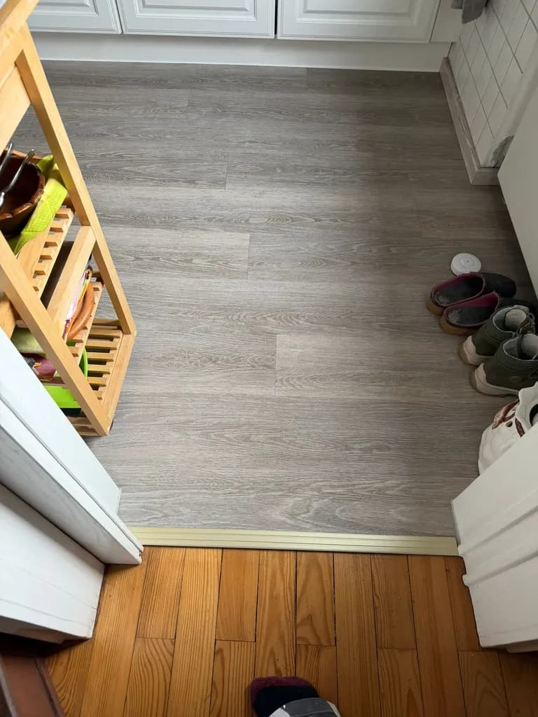 Übergang zwischen neuem Vinylboden in Holzoptik und altem Dielenboden mit Übergangsprofil aus Aluminium, verlegt vom Betrieb Siebert in einer Wohnung im Saarland.