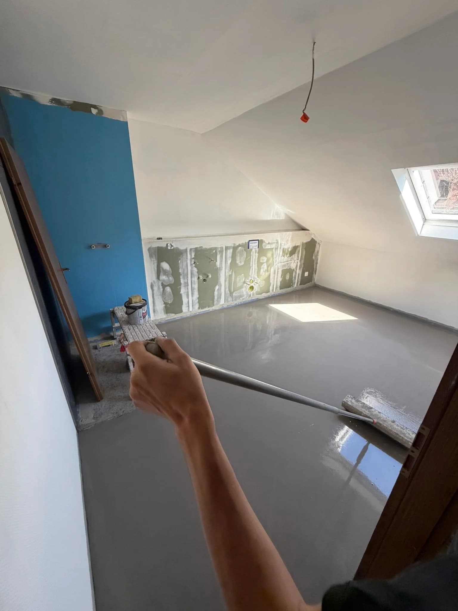 Selbstverlaufende Ausgleichsmasse wird in einem Dachgeschoss mit der Stachelwalze verteilt, Untergrundvorbereitung vor dem Belag durch den Betrieb Siebert.