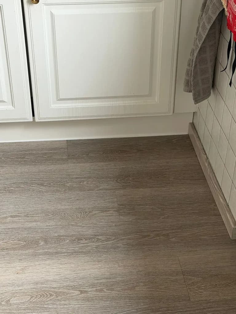 Bodenbelag in grauer Holzoptik in einer Küche bis zur Sockelleiste, verlegt vom Maler- und Stuckateurbetrieb Siebert.