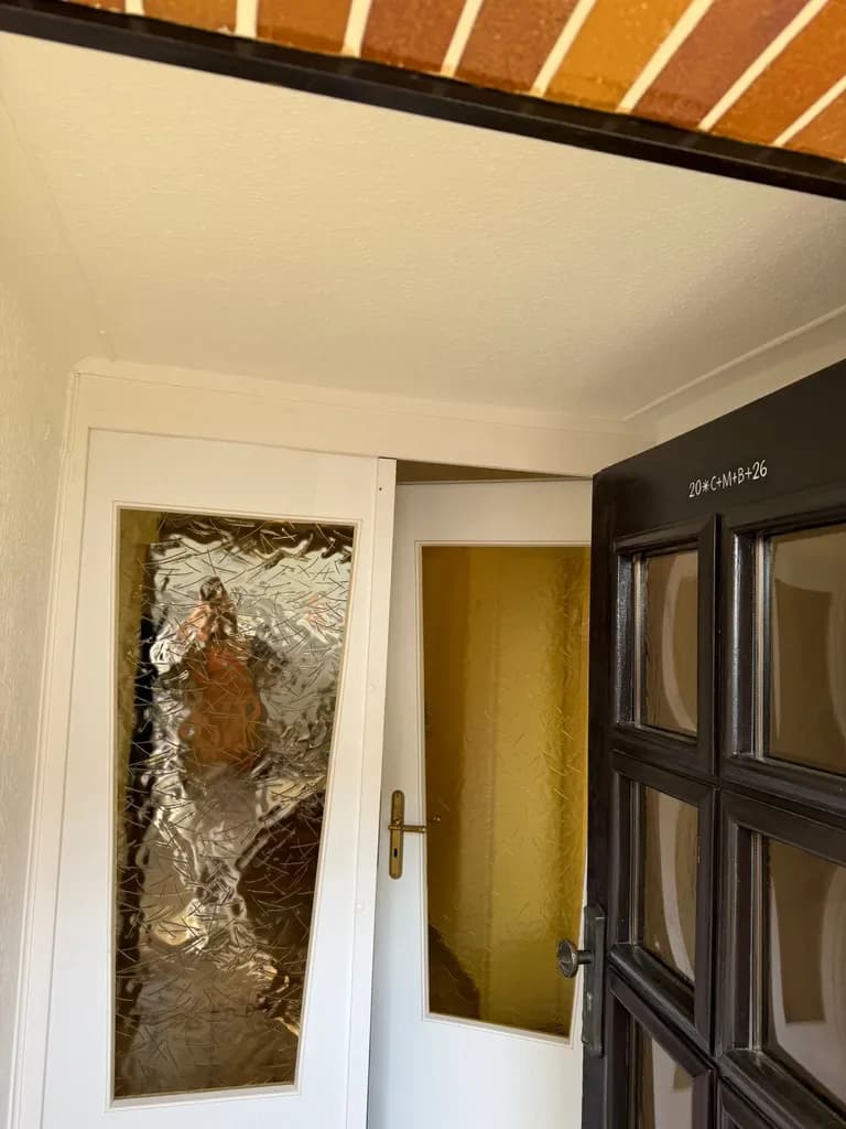 Weiß lackierte Innentür mit Zarge neben einer dunkel lackierten Holz-Haustür im Eingangsbereich, Lackierarbeit des Betriebs Siebert im Saarland.